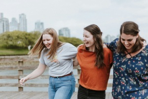 3 young women  who are walking outdoor and laughing 